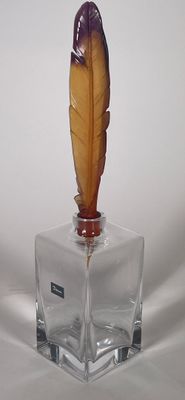 un petit vase en verre surmonté d'une plume