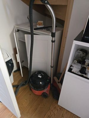 un aspirateur posé par terre à côté d'un réfrigérateur