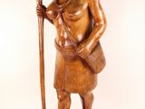 wooden statue of a woman holding a cane and a basket