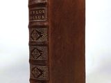 an old book with a brown leather cover sitting on a white surface