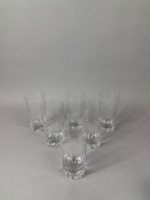 six clear glasses are lined up on a white surface