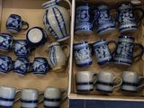 une boîte remplie de tasses à café et de mugs bleus et blancs