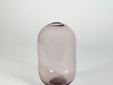 vase en verre violet posé sur une surface blanche, avec un fond blanc