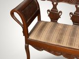 a wooden bench with a striped seat pad on it