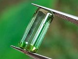un gros plan sur un morceau de verre vert tenu par une pince