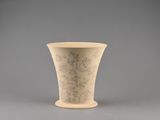 a white vase with a design on it on a gray surface