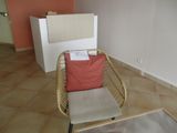 une chaise en osier avec un coussin rouge dans un coin de la pièce