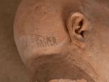 a close up of a clay head with writing on it