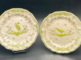 une paire d'assiettes vertes et blanches ornées d'oiseaux, posées sur une table