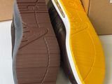 the sole of a pair of brown and yellow shoes next to a cardboard box