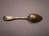an old spoon is sitting on a table with a gray background