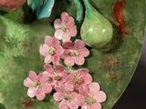 a green plate with flowers and fruit on it
