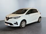 Une voiture blanche est garée dans une pièce au sol gris.