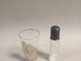 a small glass and a small bottle on a table