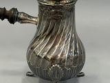 silver plated coffee pot with a wooden handle on a stand