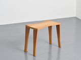 a small wooden bench in a room with a white wall