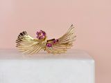 a close up of a gold ring with pink stones on top of a marble block