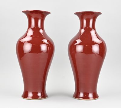 pair of red vases sitting on a white surface next to each other