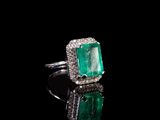 une bague en émeraude et diamant sur une surface noire