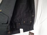 the back of a pair of black jeans laying on a bed