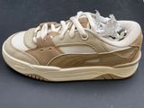 beige and white sneakers with torn laces on them on a black surface