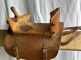 une selle de cheval en cuir posée sur un support en bois devant un fond blanc