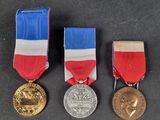 three medals are shown on a black surface with a red, white, and blue ribbon