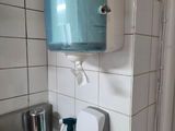 a sink with a soap dispenser and a hand towel dispenser on the wall