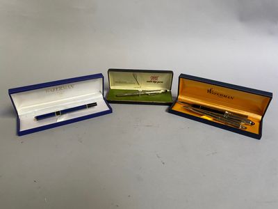 trois stylos se trouvent dans une boîte posée sur une table, sur fond blanc
