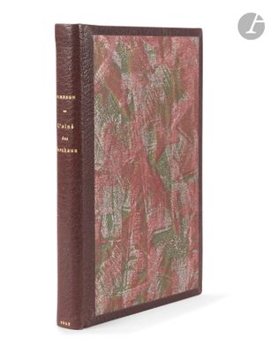 an old book with a red cover sitting on top of a white surface