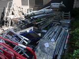 a pile of chairs and ladders outside of a building