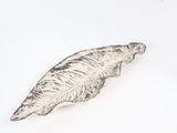 leaf shaped metal object on a white surface with a white background