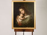 an oil painting of a woman holding a baby on a easel