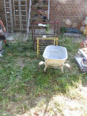 a man that is standing in the yard with a wheelbarrow