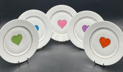 four plates with hearts painted on them sitting on a table