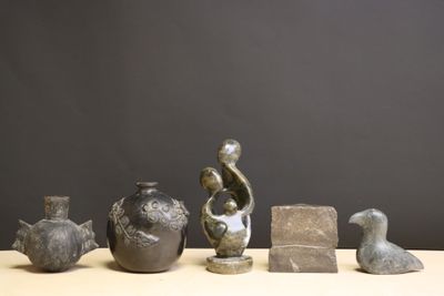 cinq vases différents posés sur une table, sur fond noir
