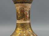 a gold vase with a picture of a man and a woman on it