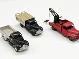 trois camions miniatures placés les uns à côté des autres sur une surface blanche