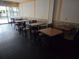 tables and chairs are lined up in a room with a large window