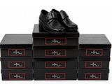 quatre boîtes noires posées sur une surface blanche, avec des chaussures noires posées dessus