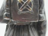silver figurine of a man with a backpack on his back
