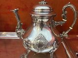 une théière en argent posée sur une table à côté d'une cuillère