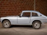 a silver car that is parked in front of a brick wall