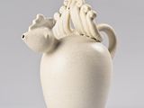 a white vase with a bird on top of it