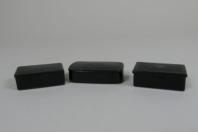 trois boîtes en plastique noir posées sur une surface blanche