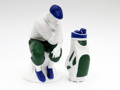 une figurine représentant un homme assis à côté d'un sac de golf