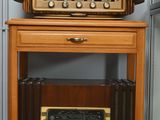 une petite table sur laquelle est posée une radio, à côté d'un réfrigérateur