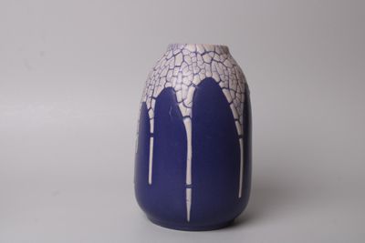 un vase bleu orné de motifs blancs, posé sur une surface blanche