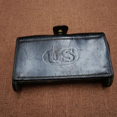 un portefeuille en cuir orné du logo « us », posé sur une surface marron