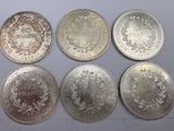 six different types of silver coins on a white surface